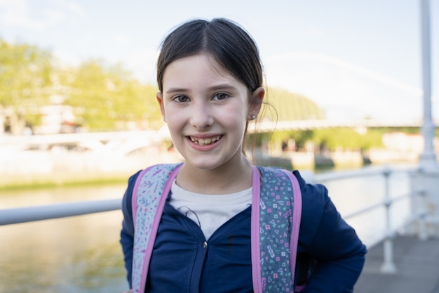 Portret van een glimlachend jong kind met schoolrugzak Gelukkig klein meisje buiten na school