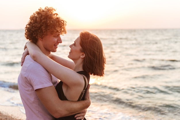Portret van een glimlachend jong paar dat bij het strand koestert