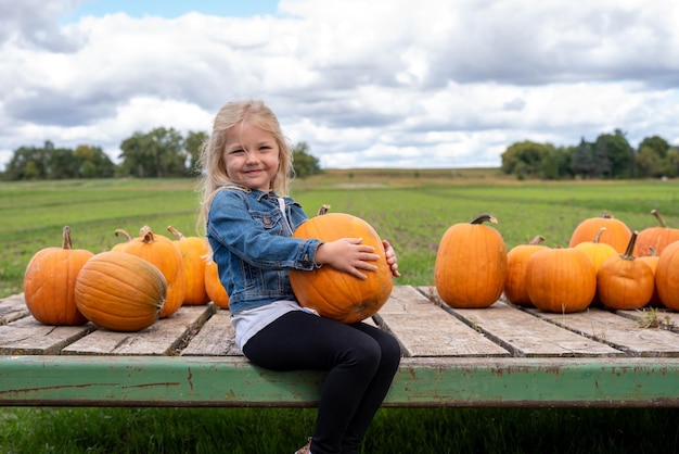 Portret van een glimlachend meisje bij pompoenen op het veld tegen de lucht
