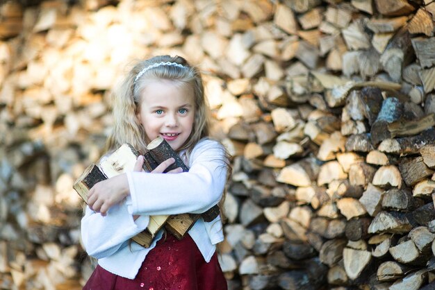 Foto portret van een glimlachend meisje dat bij hout staat