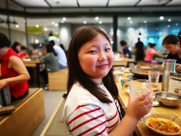 Portret van een glimlachend meisje dat eten eet in een restaurant