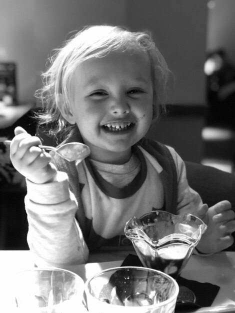 Foto portret van een glimlachend meisje dat op tafel zit