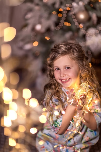 Portret van een glimlachend meisje met verlichte kerstverlichting