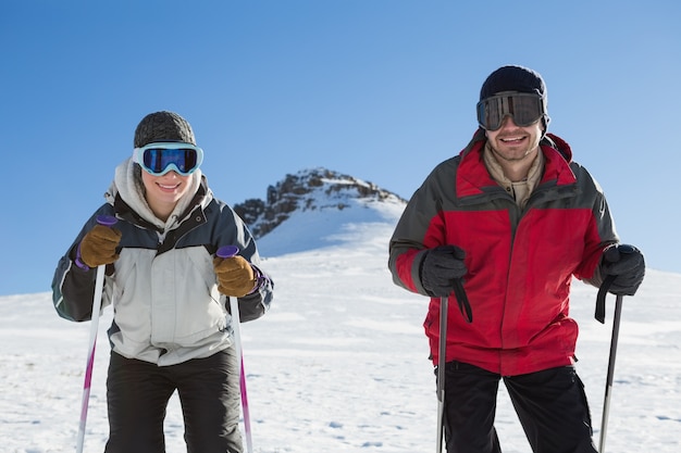 Portret van een glimlachend paar met skistokken op sneeuw