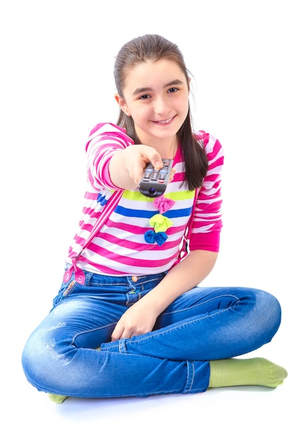 Foto portret van een glimlachend tienermeisje met een afstandsbediening terwijl ze tegen een witte achtergrond zit