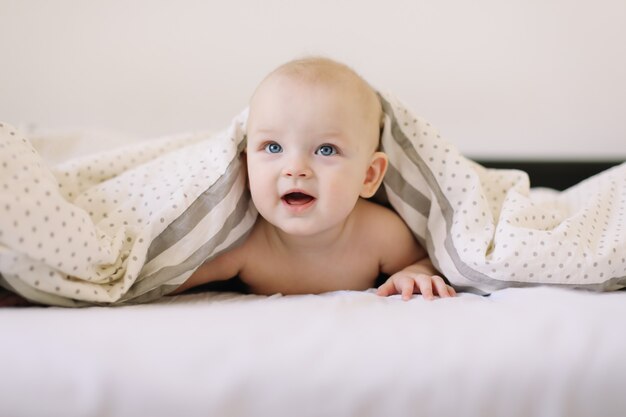 Portret van een glimlachende baby die in bed kruipt.