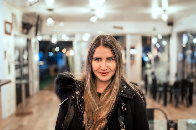 Portret van een glimlachende blanke volwassen vrouw die naar de camera kijkt in een café-pub of restaurantx9