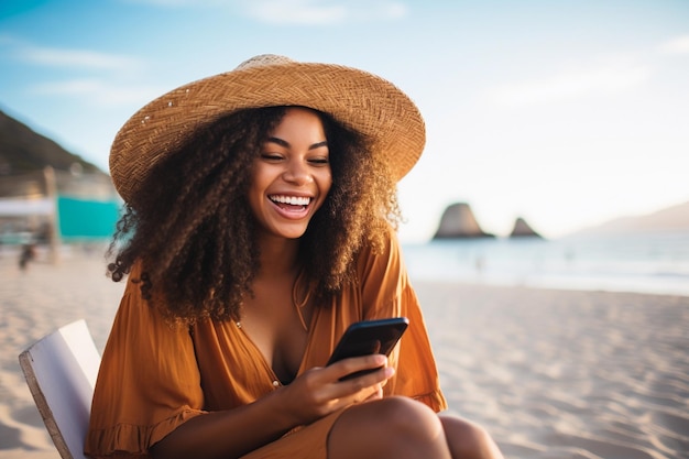 Portret van een glimlachende en gelukkige jonge Braziliaanse vrouw die op het strand in Ipanema zit en naar haar mobiel kijkt