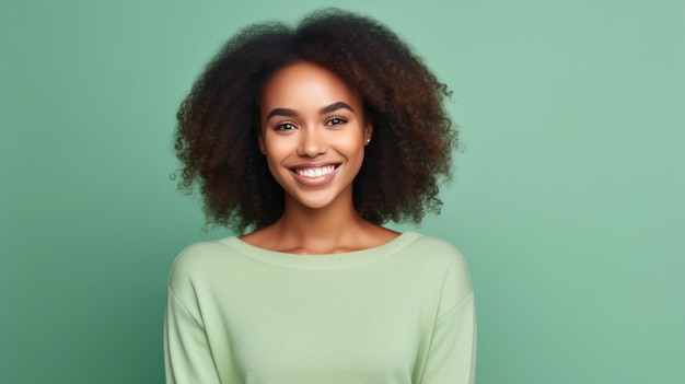 Portret van een glimlachende jonge Afrikaanse vrouw die sweater draagt die zich geïsoleerd over groene achtergrond bevindt