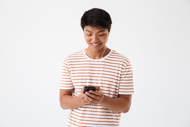 Portret van een glimlachende jonge aziatische man die aan muziek luistert