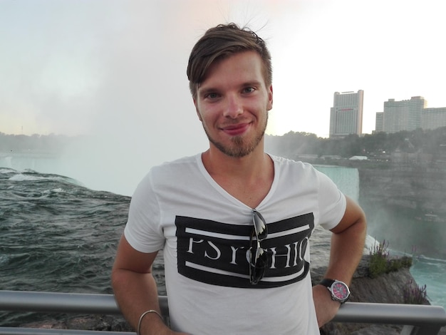 Foto portret van een glimlachende jonge man bij de niagara falls