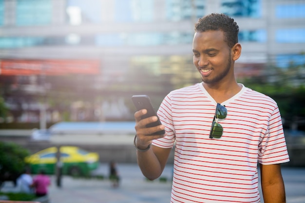 Portret van een glimlachende jonge man die buiten aan de telefoon staat