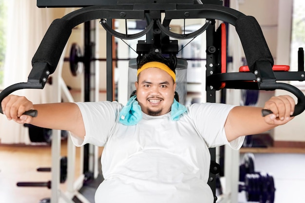 Foto portret van een glimlachende jonge man die in de sportschool oefent