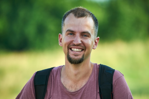 Portret van een glimlachende jonge man in een park