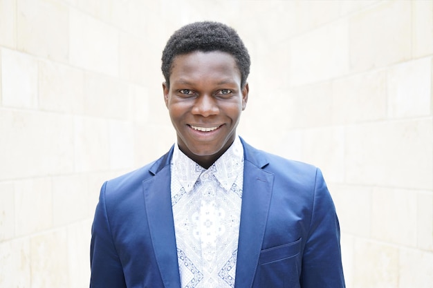 Portret van een glimlachende jonge man met een blauwe blazer tegen de muur