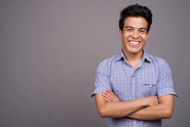 Portret van een glimlachende jonge man tegen een grijze achtergrond