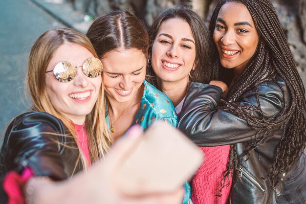 Foto portret van een glimlachende jonge vrouw die een selfie maakt met haar smartphone