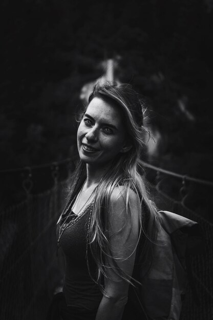 Foto portret van een glimlachende jonge vrouw die op een brug staat