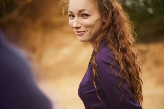 Foto portret van een glimlachende jonge vrouw die op het veld staat