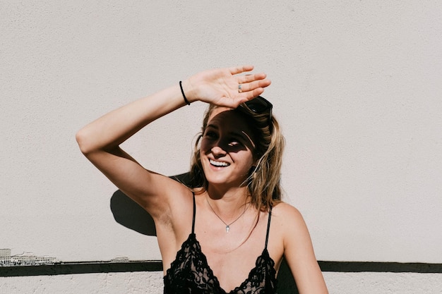 Portret van een glimlachende jonge vrouw die tegen de muur staat