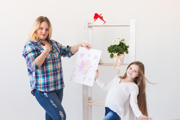 Foto portret van een glimlachende jonge vrouw die tegen de muur staat