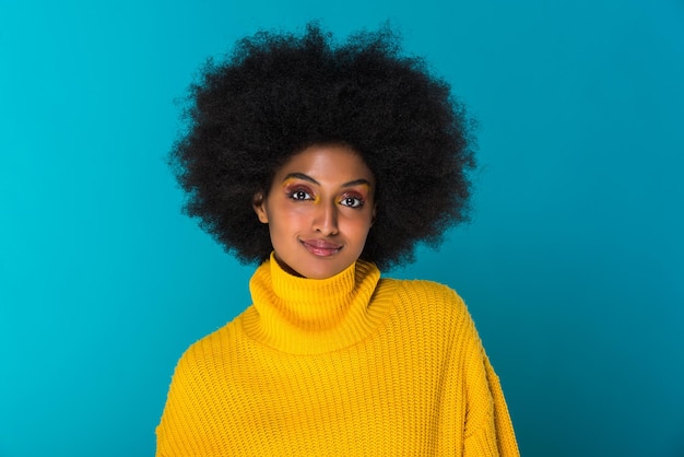 Portret van een glimlachende jonge vrouw die tegen een blauwe achtergrond staat