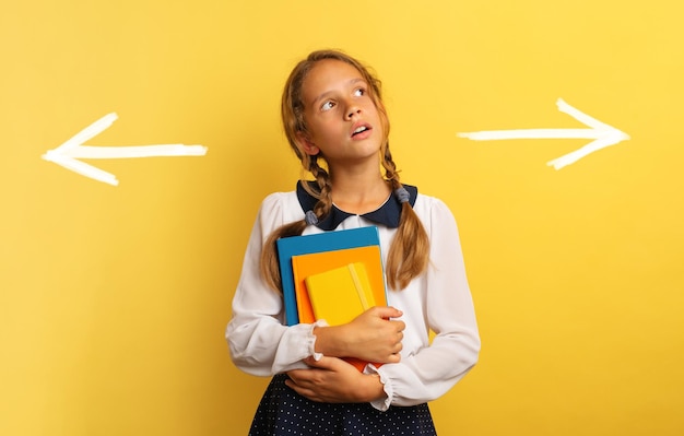 Foto portret van een glimlachende jonge vrouw die tegen een gele achtergrond staat