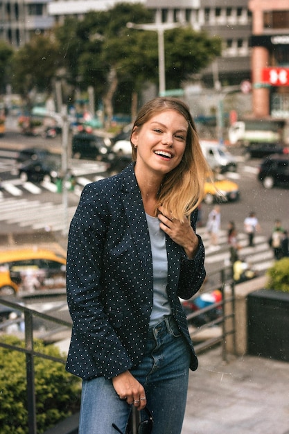 Portret van een glimlachende jonge vrouw die tegen gebouwen in de stad staat