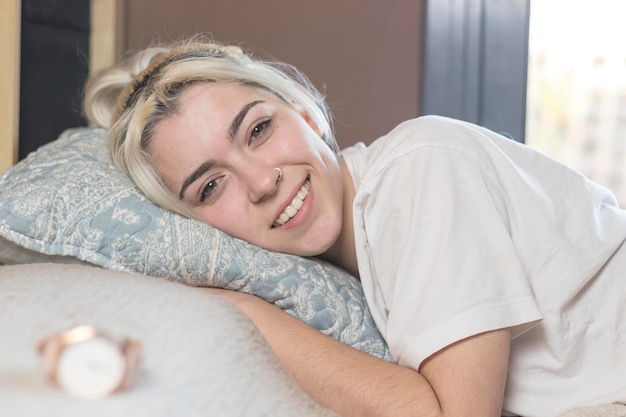 Foto portret van een glimlachende jonge vrouw die thuis op bed ontspant