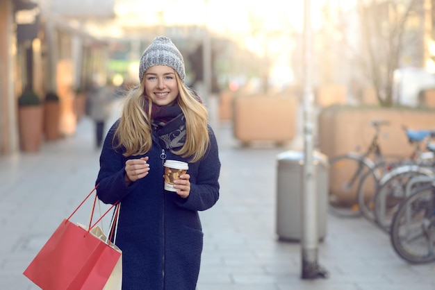 Portret van een glimlachende jonge vrouw met blond haar die op de stoep staat