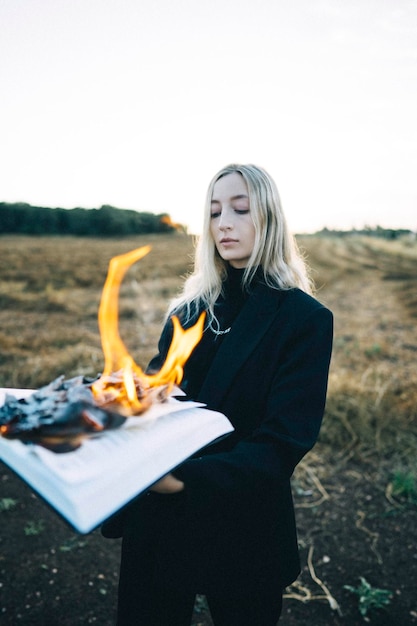 Foto portret van een glimlachende jonge vrouw met een mobiele telefoon terwijl ze op het veld zit