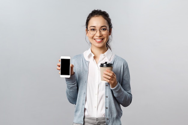 Portret van een glimlachende jonge vrouw met een telefoon op een witte achtergrond