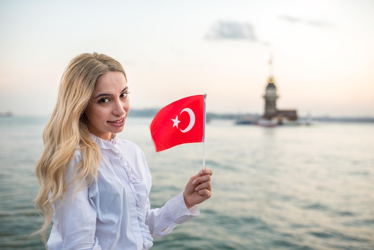 Foto portret van een glimlachende jonge vrouw met een turkse vlag op het strand tegen de hemel tijdens de zonsondergang