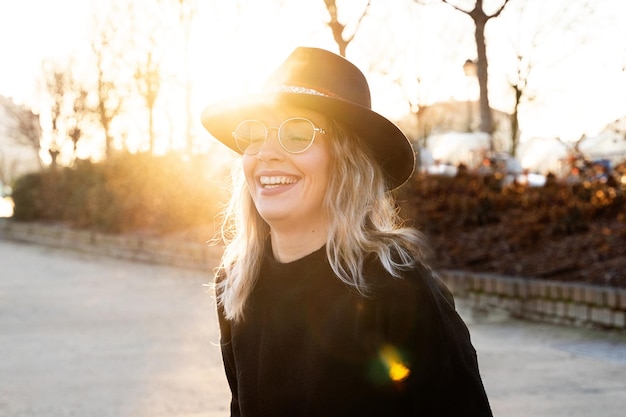 Portret van een glimlachende jonge vrouw met een zonnebril bij zonsondergang