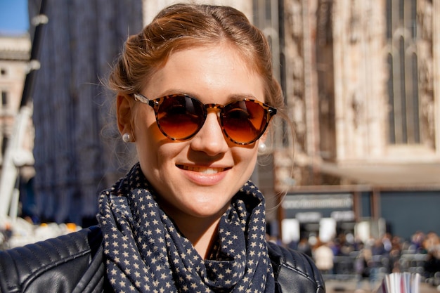 Portret van een glimlachende jonge vrouw met een zonnebril