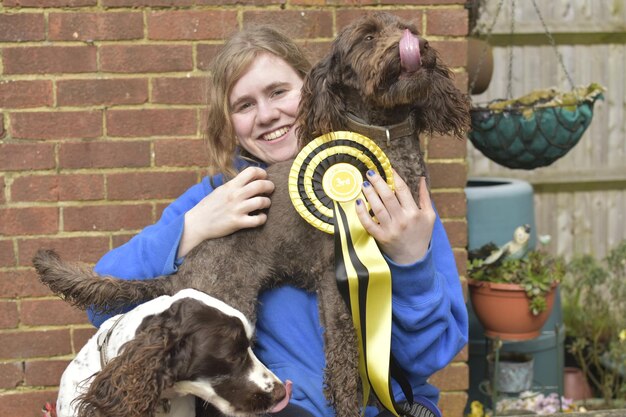 Foto portret van een glimlachende jonge vrouw met honden tegen een bakstenen muur