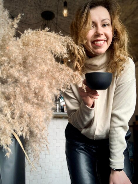 Foto portret van een glimlachende jonge vrouw met koffie op tafel