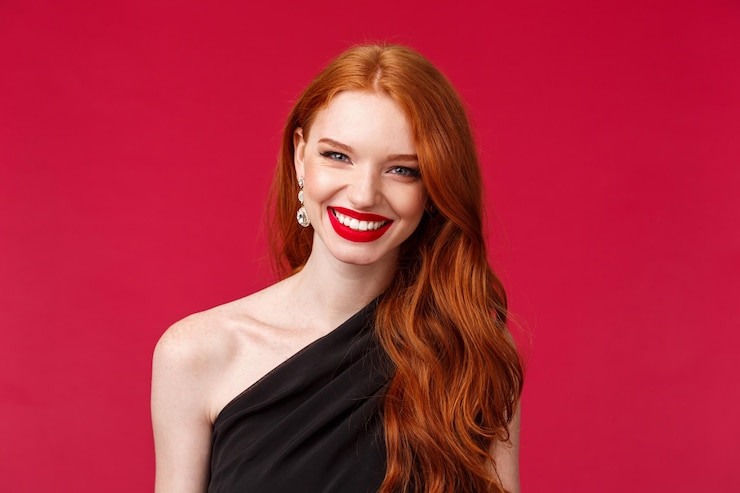 Foto portret van een glimlachende jonge vrouw op een rode achtergrond