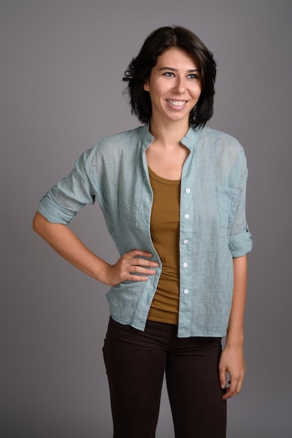 Portret van een glimlachende jonge vrouw tegen een grijze achtergrond