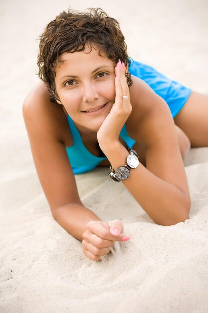 Foto portret van een glimlachende jongen die op het zand ligt