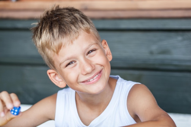 Portret van een glimlachende jongen met blauwe dobbelstenen thuis