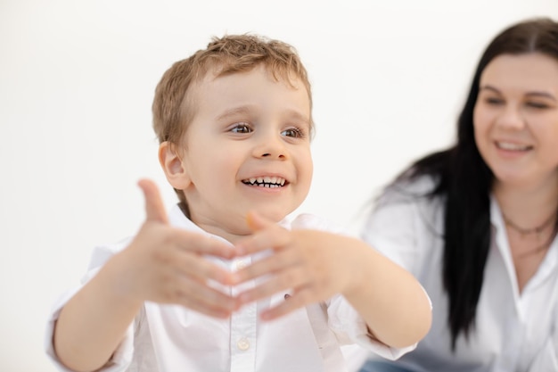 Portret van een glimlachende kleine kindjongen die plezier heeft samen met moeder die eerst communiceert met