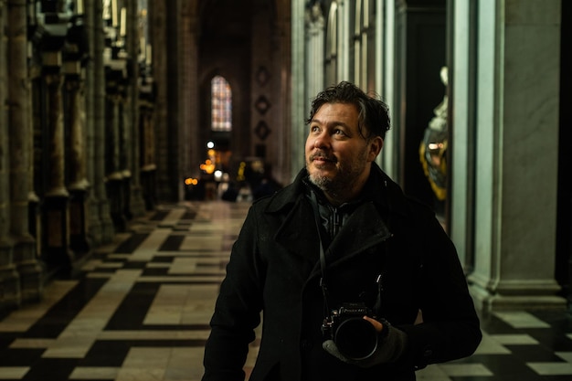 Foto portret van een glimlachende man die in de gang staat met een analoge camera