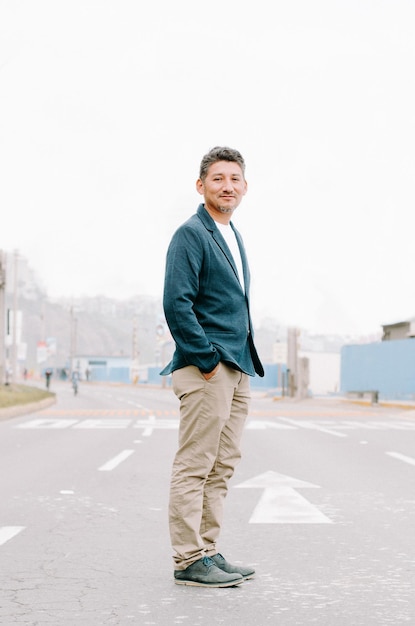 Portret van een glimlachende man die op straat staat tegen een heldere lucht