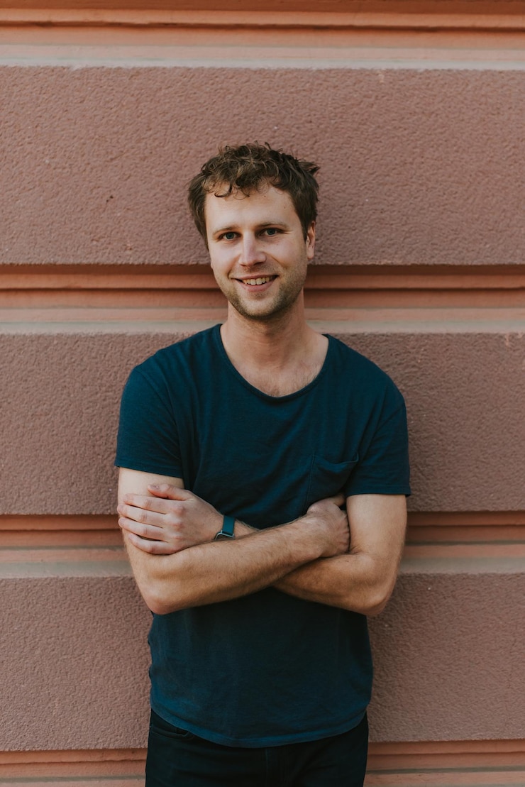 Foto portret van een glimlachende man die tegen de muur staat