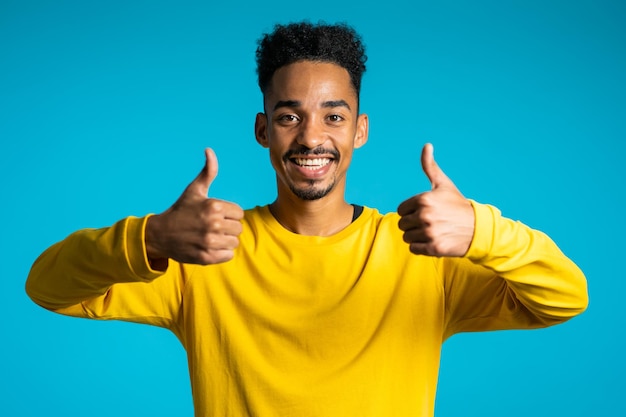 Portret van een glimlachende man die tegen een blauwe achtergrond gebaren maakt