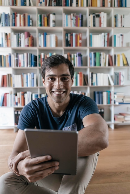 Portret van een glimlachende man die thuis een tablet vasthoudt