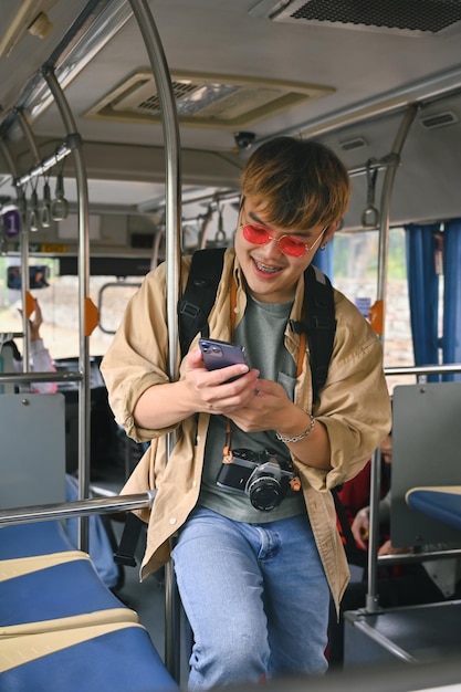 Portret van een glimlachende man, een toerist die met de bus reist en een mobiele telefoon gebruikt.