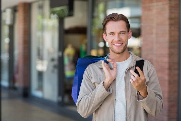 Portret van een glimlachende man met behulp van zijn telefoon