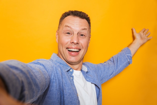 Foto portret van een glimlachende man van middelbare leeftijd die een selfie neemt